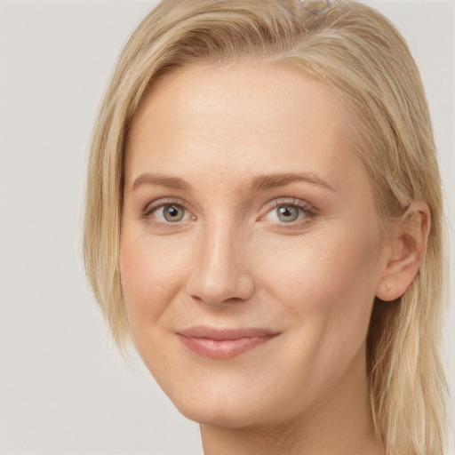 Joyful white young-adult female with long  blond hair and grey eyes