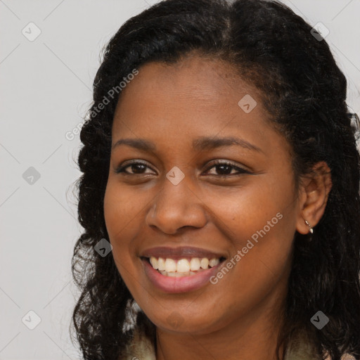 Joyful black young-adult female with long  brown hair and brown eyes