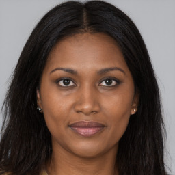 Joyful black young-adult female with long  brown hair and brown eyes