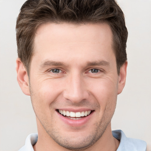 Joyful white young-adult male with short  brown hair and grey eyes