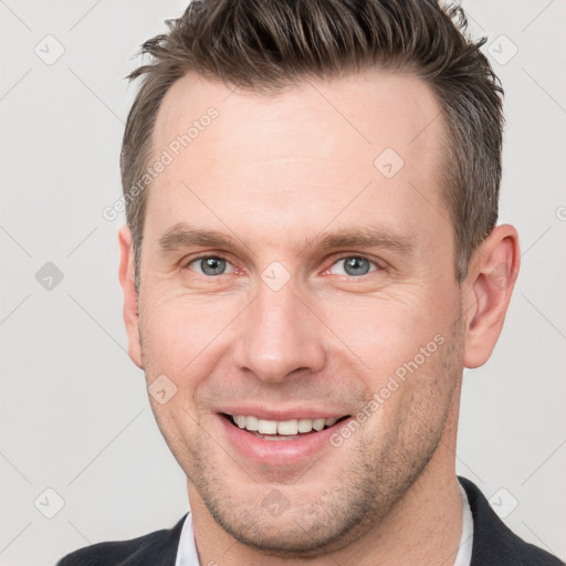 Joyful white young-adult male with short  brown hair and grey eyes