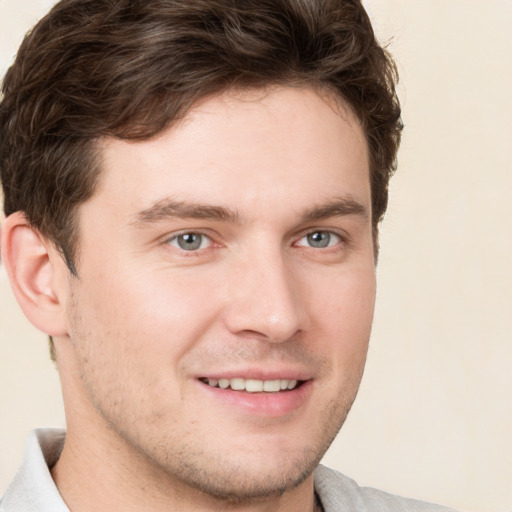 Joyful white young-adult male with short  brown hair and grey eyes