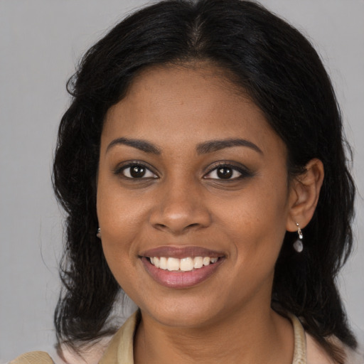 Joyful black young-adult female with long  brown hair and brown eyes