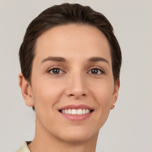 Joyful white young-adult female with short  brown hair and grey eyes