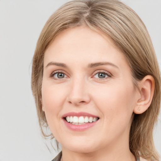 Joyful white young-adult female with medium  brown hair and grey eyes