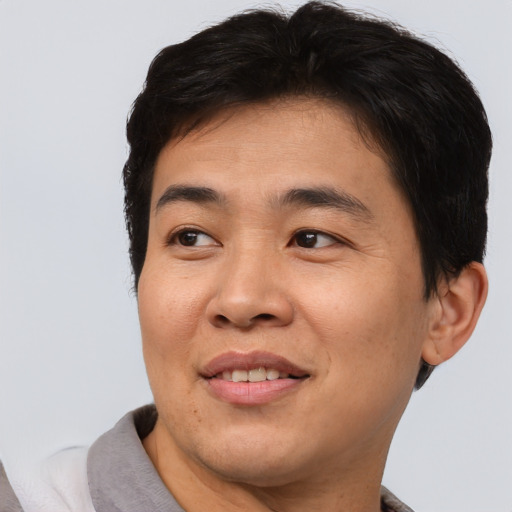 Joyful asian young-adult male with short  brown hair and brown eyes
