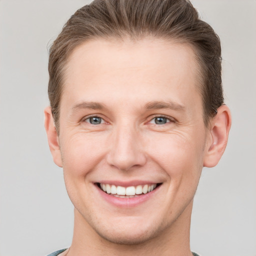 Joyful white young-adult male with short  brown hair and grey eyes