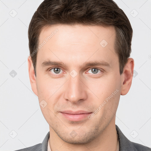 Joyful white young-adult male with short  brown hair and grey eyes