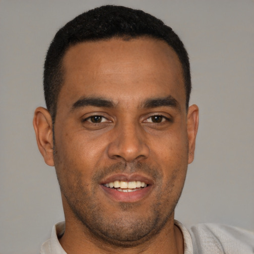 Joyful black young-adult male with short  brown hair and brown eyes