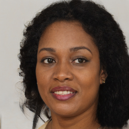 Joyful black young-adult female with long  brown hair and brown eyes