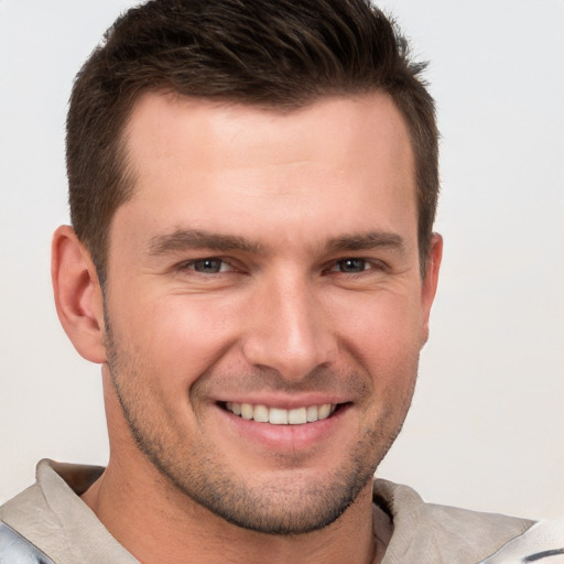 Joyful white young-adult male with short  brown hair and grey eyes