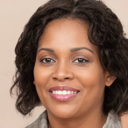 Joyful black young-adult female with long  brown hair and brown eyes