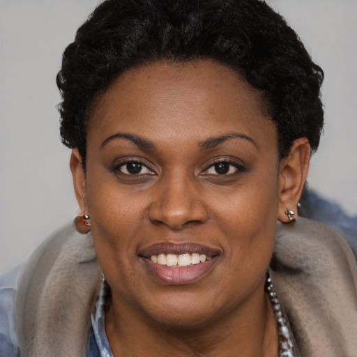 Joyful black young-adult female with short  black hair and brown eyes