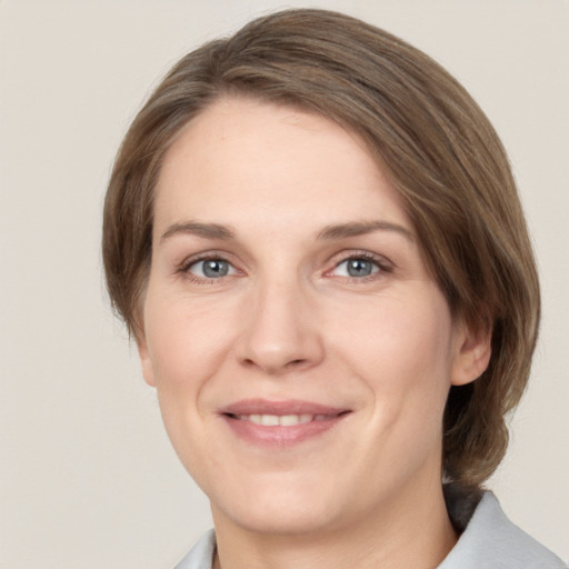 Joyful white young-adult female with medium  brown hair and grey eyes