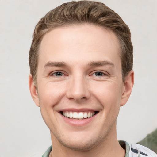 Joyful white young-adult male with short  brown hair and grey eyes