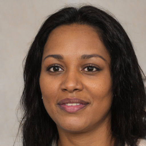 Joyful black adult female with long  black hair and brown eyes