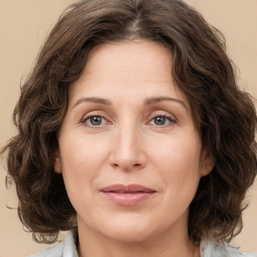 Joyful white adult female with medium  brown hair and green eyes