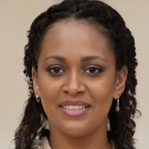 Joyful black young-adult female with long  brown hair and brown eyes