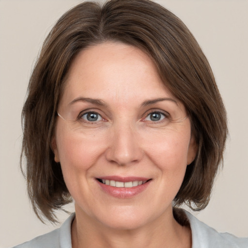 Joyful white adult female with medium  brown hair and grey eyes