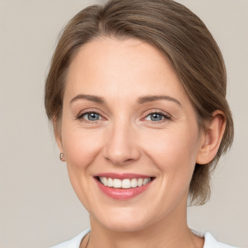 Joyful white young-adult female with medium  brown hair and grey eyes