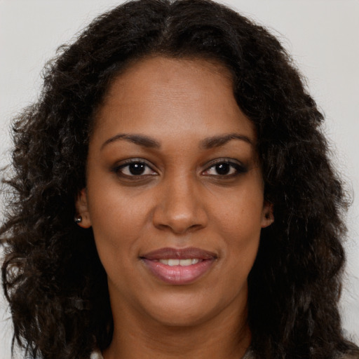 Joyful black young-adult female with long  brown hair and brown eyes