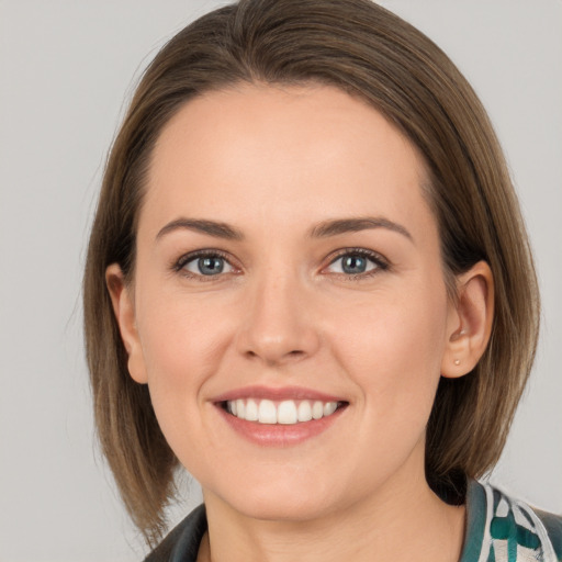 Joyful white young-adult female with medium  brown hair and grey eyes