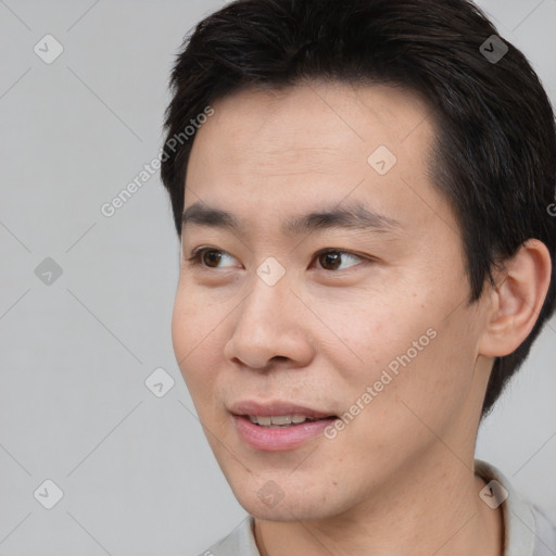 Joyful asian young-adult male with short  brown hair and brown eyes