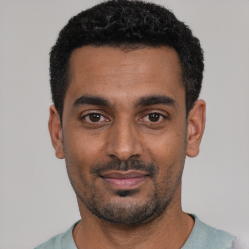 Joyful black young-adult male with short  black hair and brown eyes