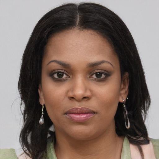 Joyful black young-adult female with long  brown hair and brown eyes