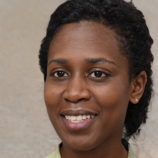 Joyful black young-adult female with short  black hair and brown eyes