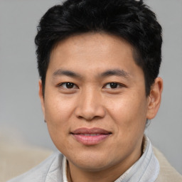 Joyful asian adult male with short  brown hair and brown eyes