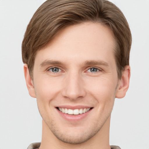 Joyful white young-adult male with short  brown hair and grey eyes