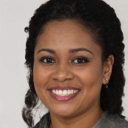 Joyful black young-adult female with long  brown hair and brown eyes