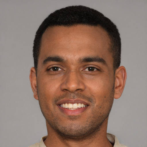 Joyful black young-adult male with short  black hair and brown eyes