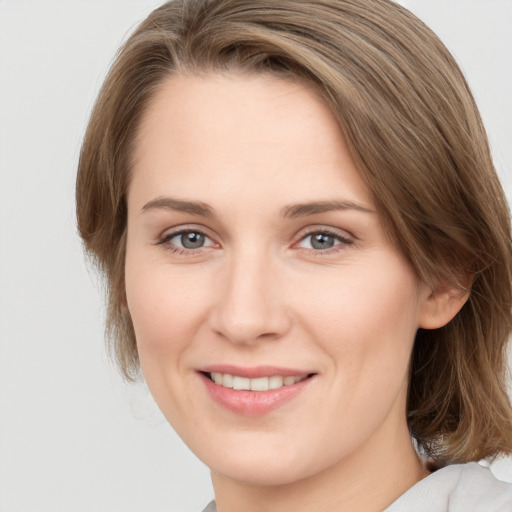 Joyful white young-adult female with medium  brown hair and grey eyes