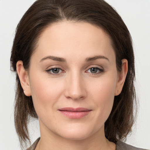 Joyful white young-adult female with medium  brown hair and grey eyes