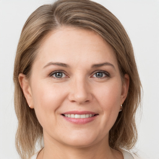 Joyful white young-adult female with medium  brown hair and grey eyes