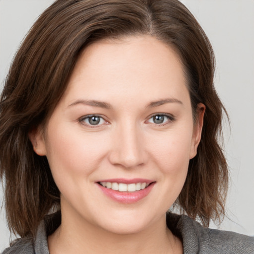 Joyful white young-adult female with medium  brown hair and grey eyes