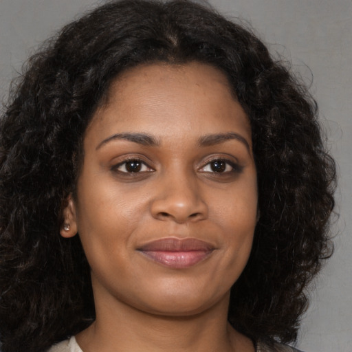 Joyful black young-adult female with long  brown hair and brown eyes