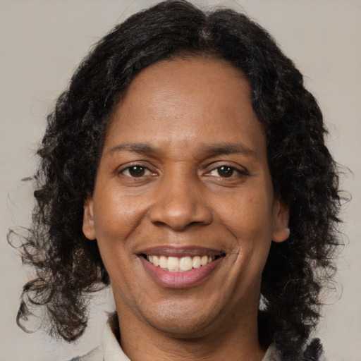 Joyful black adult female with long  brown hair and brown eyes