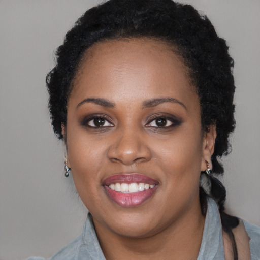 Joyful black young-adult female with long  black hair and brown eyes