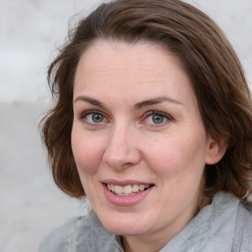 Joyful white adult female with medium  brown hair and blue eyes