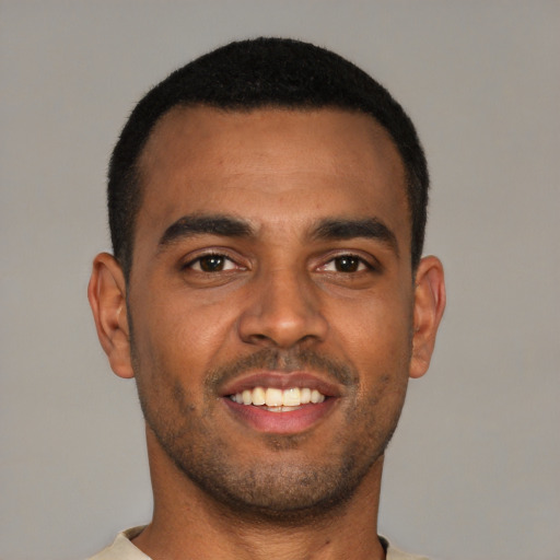 Joyful black young-adult male with short  brown hair and brown eyes