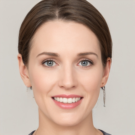 Joyful white young-adult female with medium  brown hair and grey eyes