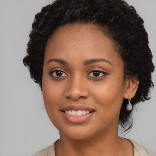 Joyful black young-adult female with long  black hair and brown eyes