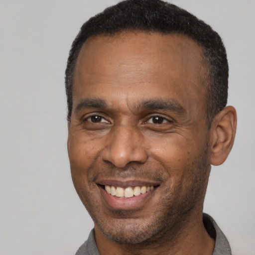 Joyful black adult male with short  black hair and brown eyes