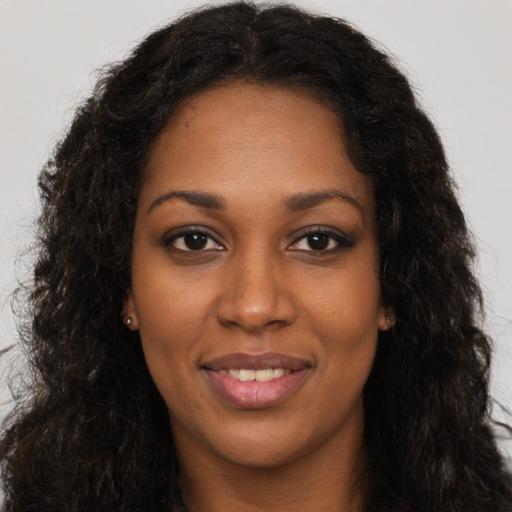 Joyful black young-adult female with long  brown hair and brown eyes