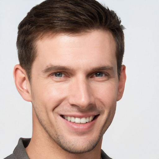 Joyful white young-adult male with short  brown hair and grey eyes