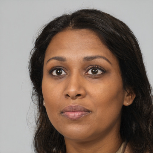 Joyful black adult female with long  brown hair and brown eyes
