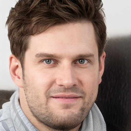 Joyful white young-adult male with short  brown hair and grey eyes